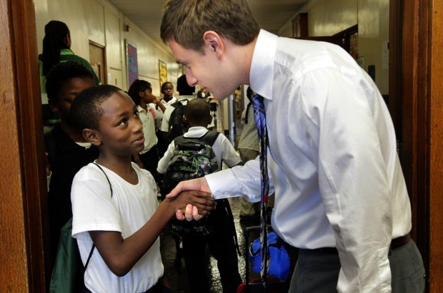 student shaking hands with teacher in hallway
