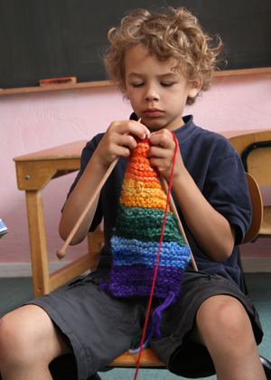 boy knitting a striped scarf
